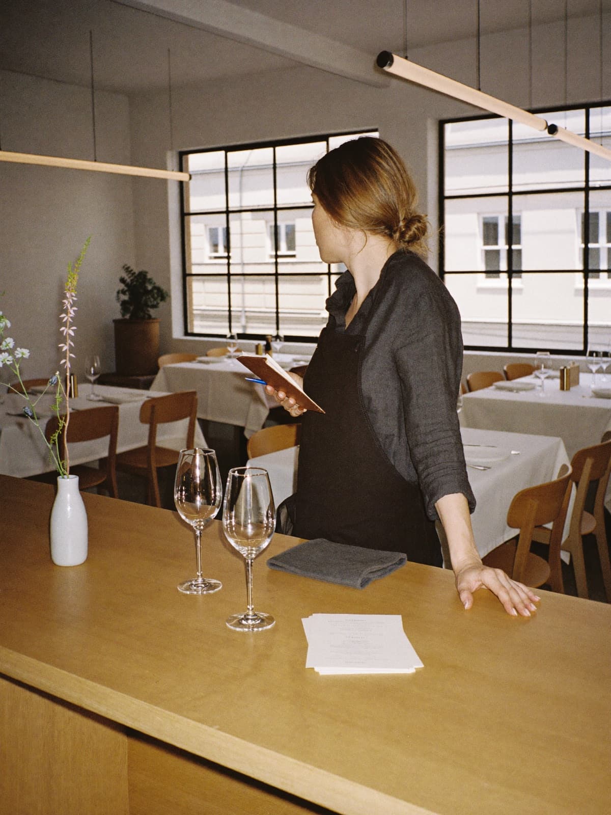 Gastgeberin in einem warm beleuchteten Restaurant kurz vor Service-Beginn