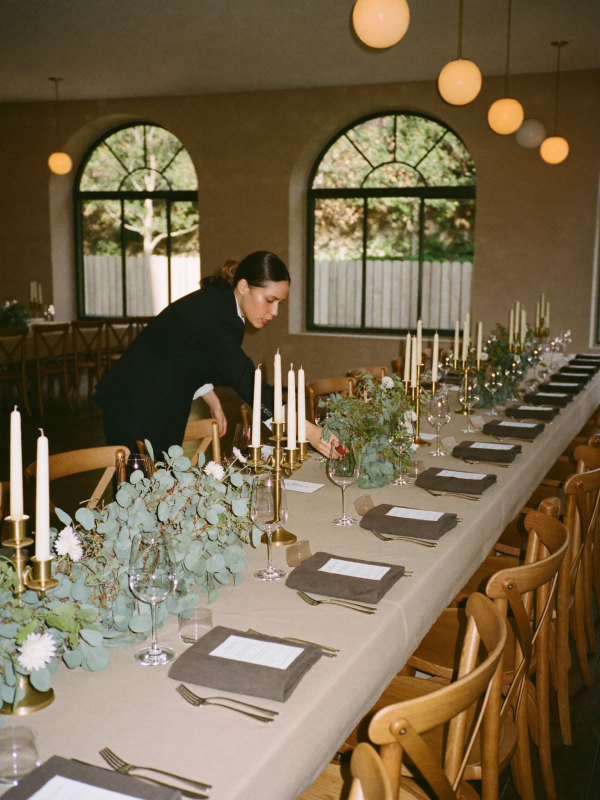 Eindeckung in einer Eventlocation: Banketttafel mit Eukalyptus-Centerpieces und Kerzen wird gerichtet